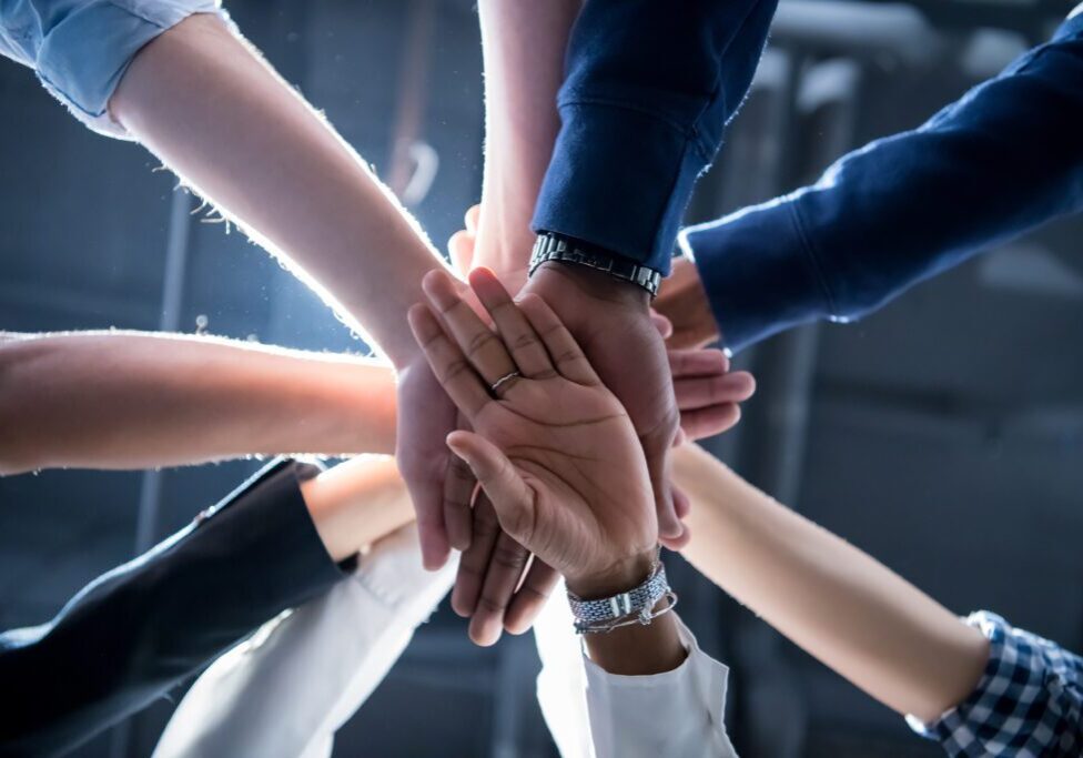 Several people stack their hands together in a gesture of teamwork and unity.